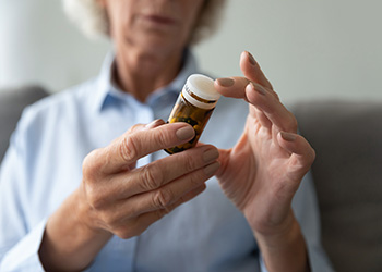 An older woman looking at the instructions on a bottle of pills