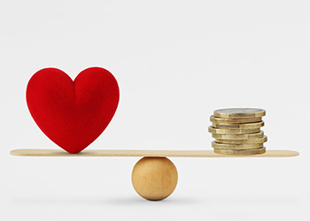 A seesaw with a heart on one side and a pile of coins on the other