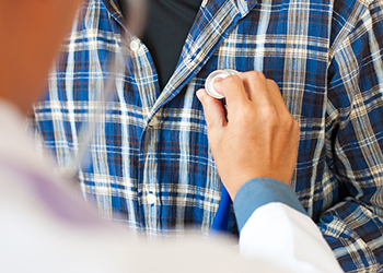 A patient has his heart examined by a doctor with a stethoscope