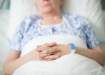 An older woman dozes lying in a hospital bed