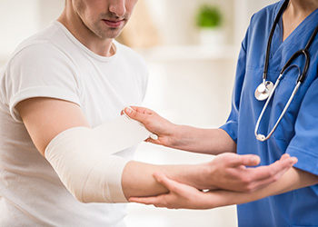 A person gets their arm bandaged in an emergency department