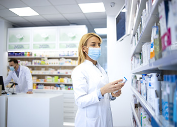 A pharmacist taking medication off a shelf in a pharmacy