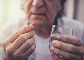 A man holds a pill and a glass of water