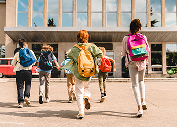 A group of children running to school wearing backpacks