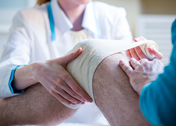 A nurse bandaging a knee