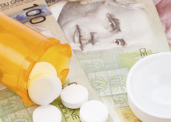 A pill bottle on a bed of Canadian bank notes