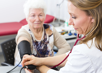 A nurse taking an older woman's blood pressure