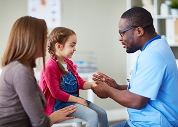 A nurse examines a young girl with her mother looking on