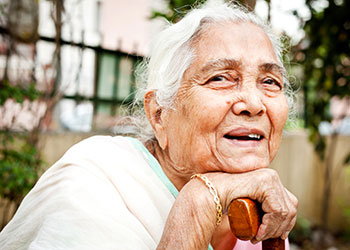 An older woman leaning on a walking stick