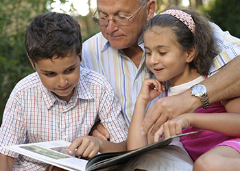 A grandfather reading to his two grandchildren