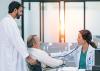 A doctor listens to the heartbeat of an older man in a hospital setting