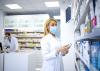 A pharmacist taking medication off a shelf in a pharmacy