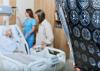 A senior women sits in a hospital bed while a doctor looks at a brain scan