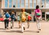 A group of children running to school wearing backpacks