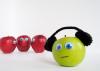 Three red apples and one green apple wearing headphones