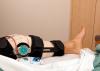 A man lying on a hospital bed wearing a knee brace